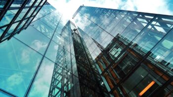 A striking view of a modern glass skyscraper reflecting the sky and clouds.