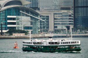 A Star Ferry crosses Victoria Harbour with Hong Kong skyline in the background.