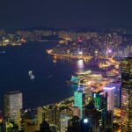 Stunning nighttime view of Hong Kong Island with illuminated skyscrapers and vibrant cityscape across Victoria Harbor.